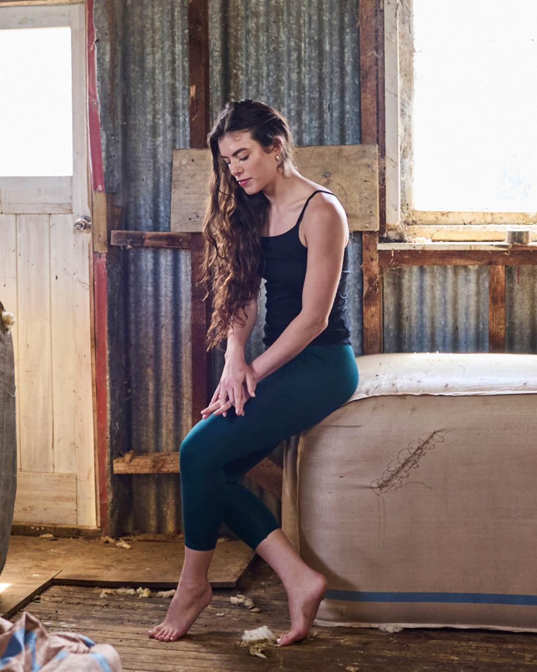 Pine green merino wool base pant, slim tapered leg, worn relaxed — earthy tone suits layering or solo wear.